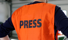 Photo of a member of the press in orange vest