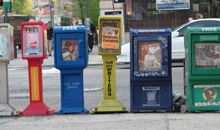 Photo of newspaper stands on busy street corner